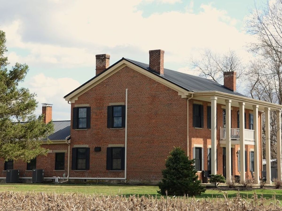 Historic brick colonial house with white columns and a broad lawn